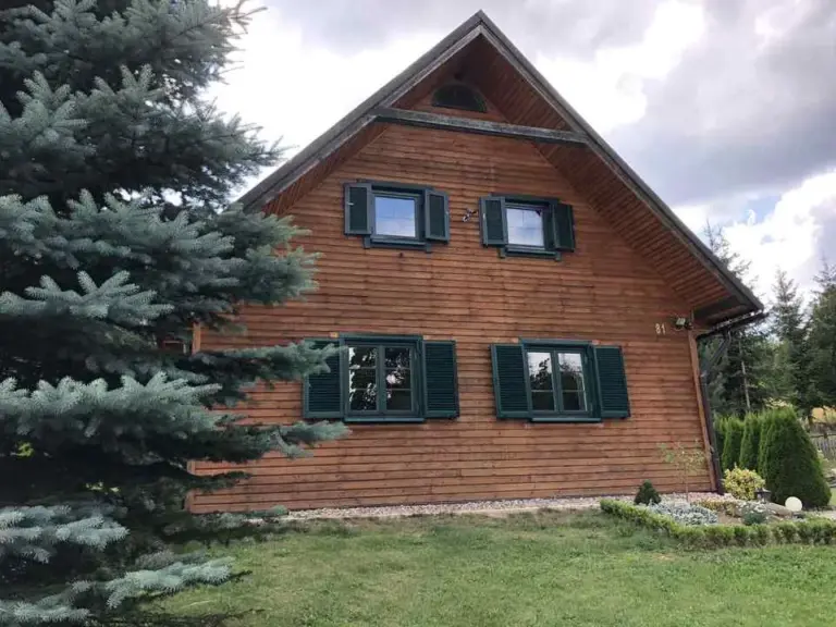 Aluminium-Fensterläden an einem Holzhäuser von NORTA. Schützt vor Wetter, gibt dem Haus eine elegante Optik.