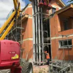 Montagearbeiten an einem Gebäude mit Kran und Gerüst. Hochwertige Lösung für professionelle Baumaßnahmen von NORTA.