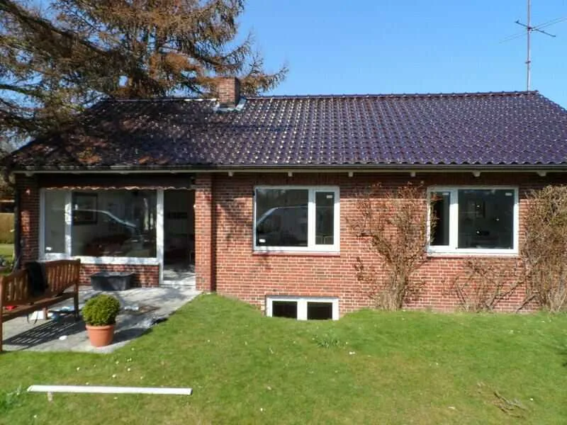 Gartenansicht eines Backsteinhauses mit neuen Fenstern von NORTA. Hochwertige Fenster für optimalen Lichteinfall und Isolierung.