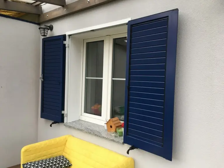 Blauer Aluminium-Fensterladen von NORTA. Stilvolle Lösung für Witterungsschutz und Privatsphäre bei Fenstern.