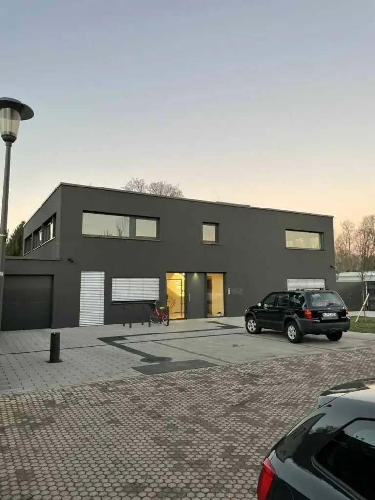 Modernes Gebäude mit dunkler Fassade, Fenstern und Tür im Vordergrund. Hochwertige Architektur von NORTA.