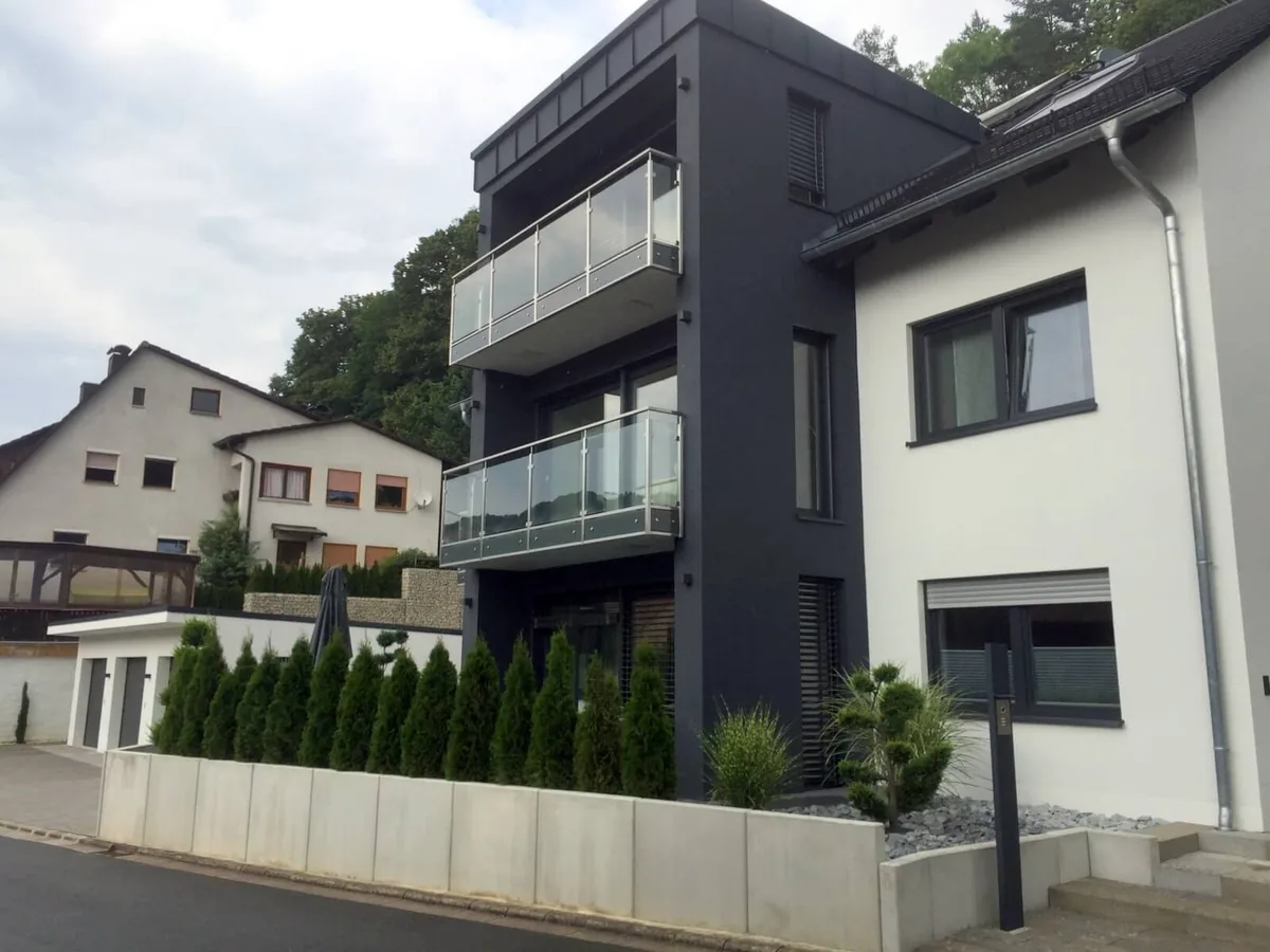 Moderne Hausfassade mit grauen und weißen Elementen sowie großen Fenstern von NORTA. Stilvolles Design für ein attraktives Zuhause.