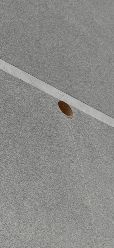 Präzise, runde Kernbohrung in einem grauen Strukturputz an der Außenfassade eines Gebäudes.