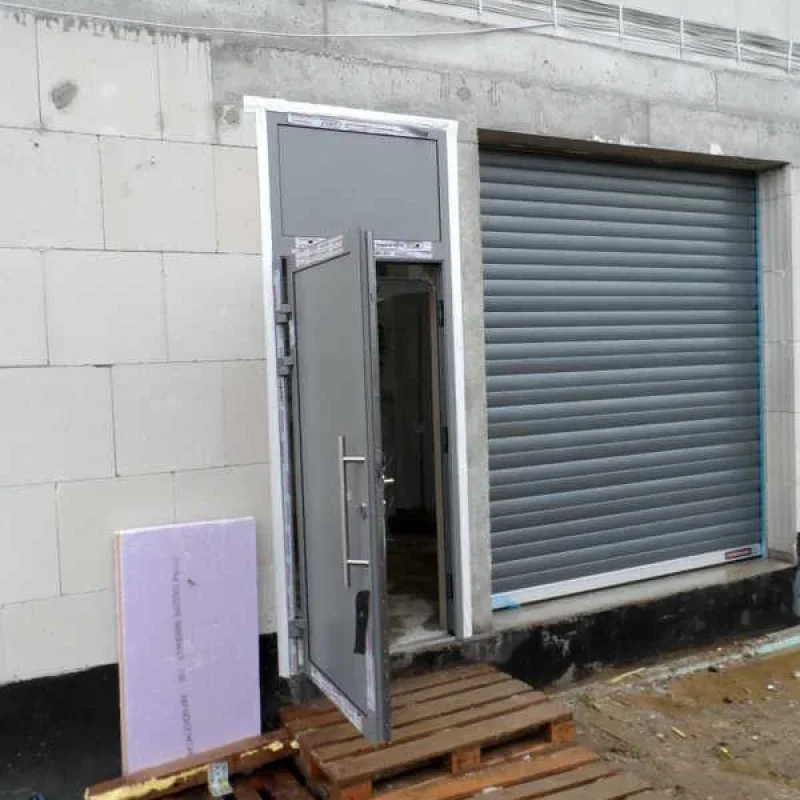 Graue Aluminium-Haustür mit Rolladen von NORTA. Funktionale Lösung für modernen Eingangsbereich.