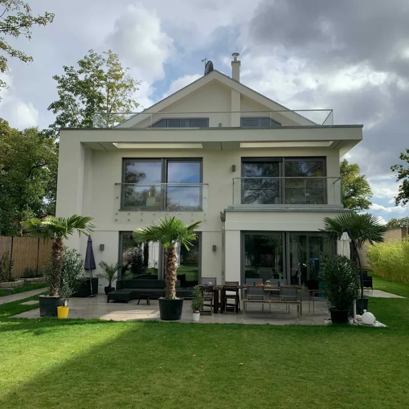 Modernes Haus mit Alufenstern und Glasgeländer von NORTA. Stilvolle Gestaltung mit hochwertiger Verglasung für optimale Helligkeit.