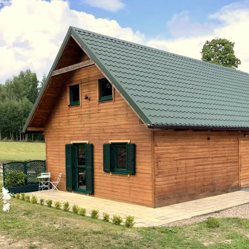 Grünes Aluminium-Fensterladen an einem Holzhaus von NORTA. Moderne und stilvolle Lösung für klassischen Hausstil.
