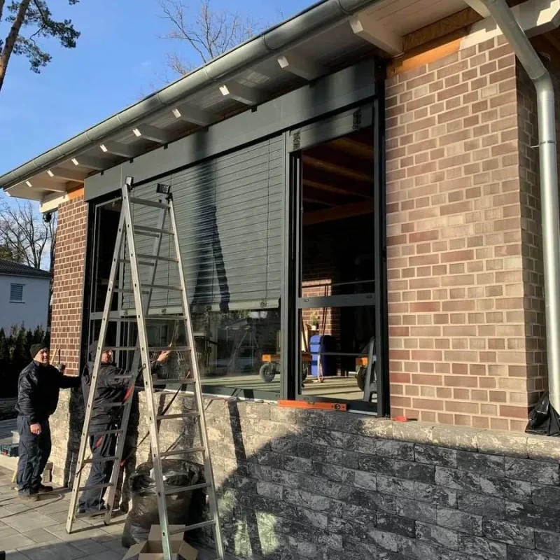 Alukonstruktion mit integrierten Raffstoren von NORTA, montiert an einem modernen Anbau für optimalen Sonnenschutz und Privatsphäre.