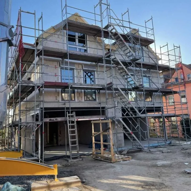 Im Bau befindliches Doppelhaus in Köln mit Gerüst. NORTA bietet maßgeschneiderte Lösungen für moderne Fenster und Türen.