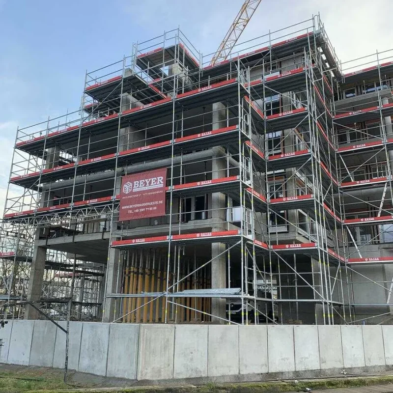 Baugerüst an einem Flussufer, das ein neues Gebäude von NORTA umgibt. Struktur in Errichtung für moderne urbane Entwicklung.