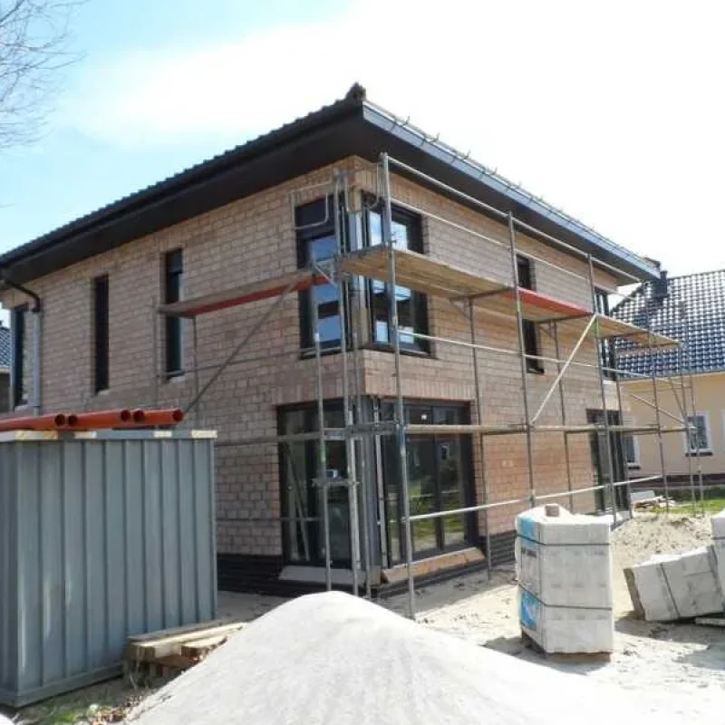 Doppelhaus im Bau mit Gerüst und anthrazitfarbenen Schüco Fenstern von NORTA. Hochwertige Bauqualität und moderne Fensterlösungen.