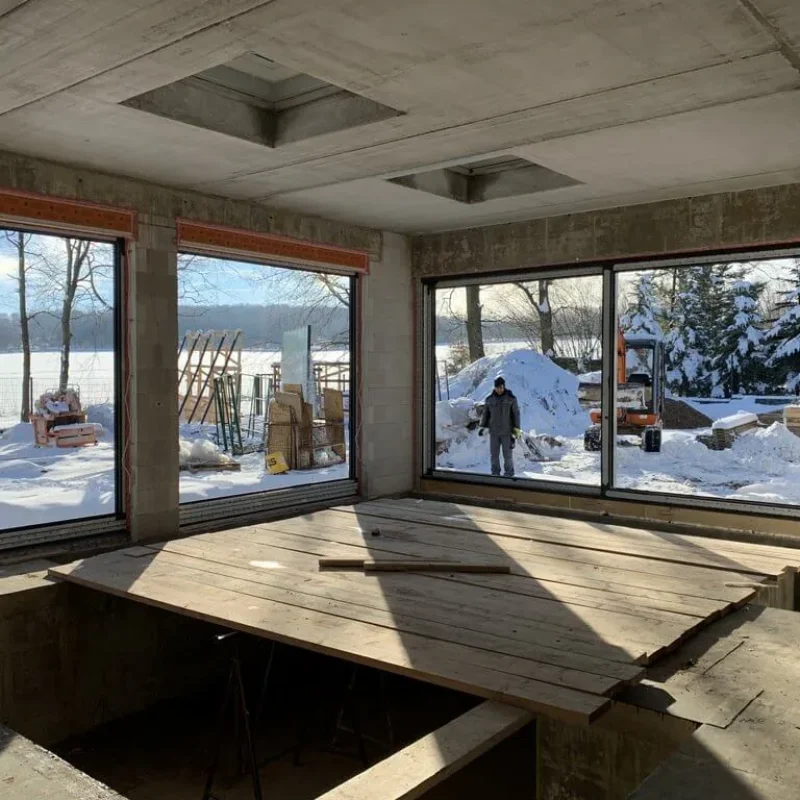 Innenraum eines Bauprojekts von NORTA mit großen Fenstern und Blick auf eine schneebedeckte Landschaft.