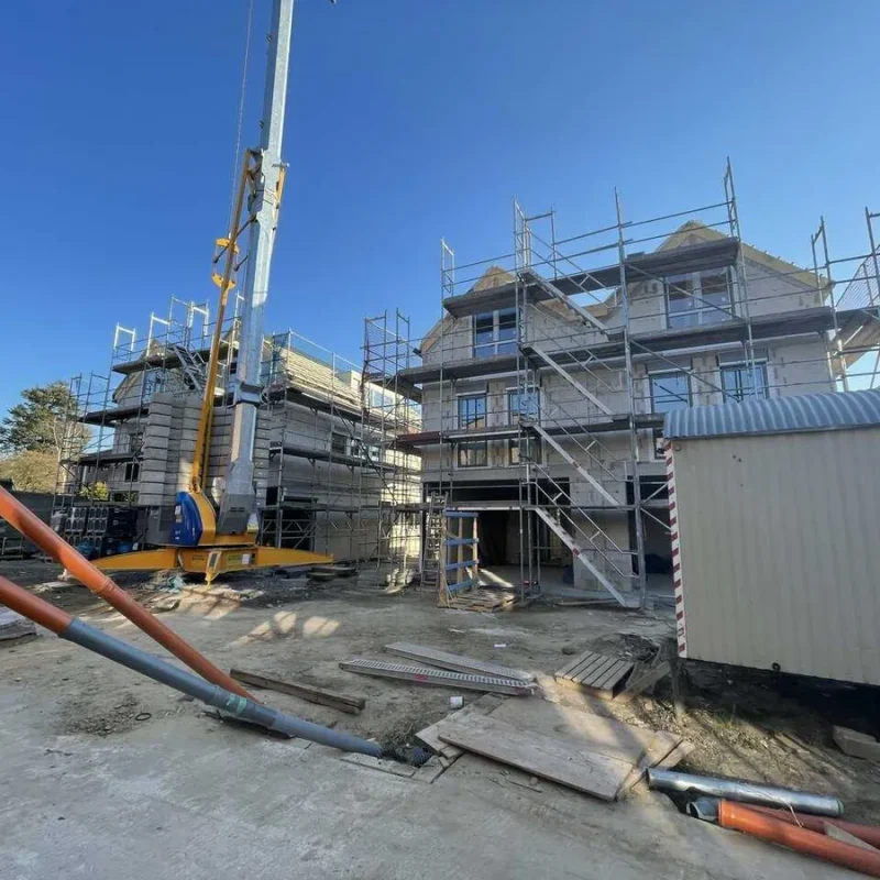 Baustelle eines Doppelhauses in Köln mit Gerüsten von NORTA. Fortschritt der Bauarbeiten bei sonnigem Wetter.