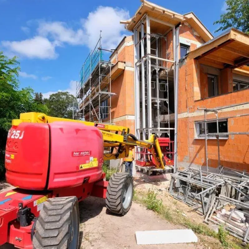 Baustellenszene mit Fenstermontage an einem Wohnhaus. Hebebühne im Einsatz für den Aufbau. Hohe Bauqualität von NORTA.