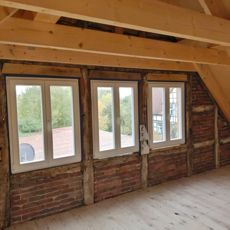 Gemütliches Dachgeschoss mit weißen Holzfenstern von NORTA. Ideal für helle und einladende Räume mit natürlichem Licht.