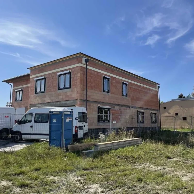 Rohbau eines Einfamilienhauses in Wien mit Gartenansicht und Umzäunung. Bauprojekt für modernes Wohnen mit hochwertigen Fenstern.