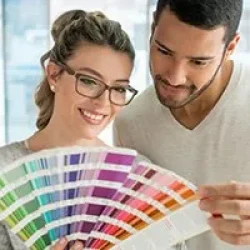 Zwei Personen betrachten eine Farbpalette. Beratung zur Farbauswahl für Fenster und Türen bei NORTA.