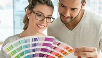 Zwei Personen betrachten eine Farbpalette. Beratung zur Farbauswahl für Fenster und Türen bei NORTA.