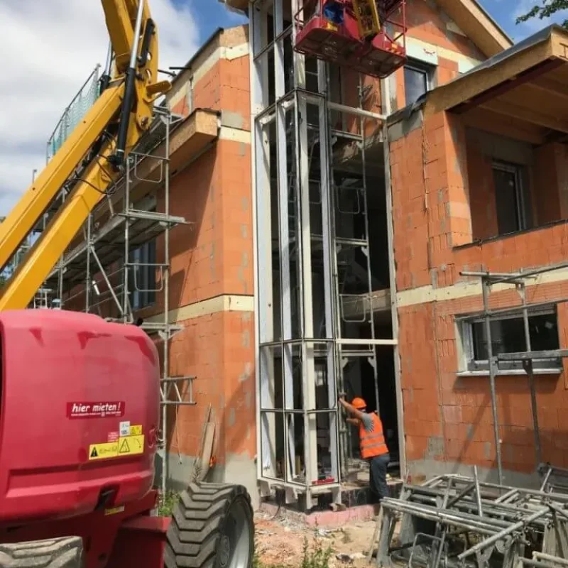 Fassadenbau bei einem Wohnhaus, Arbeiter auf Hebebühne. NORTA sorgt für effiziente Bauprojekte mit moderner Technologie.