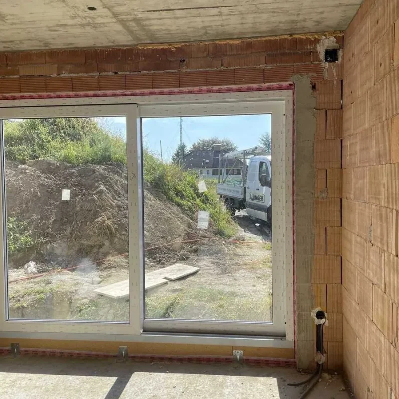 Großes weißes Fenster in einem Rohbau. Perfekt für lichtdurchflutete Räume und energieeffizientes Wohnen bei NORTA.