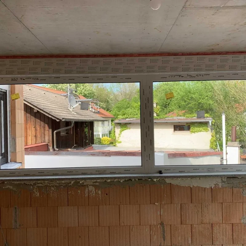 Großes Fenster in Rohbau von NORTA mit Blick auf Nachbarhaus. Ideal für helle, energieeffiziente Räume.