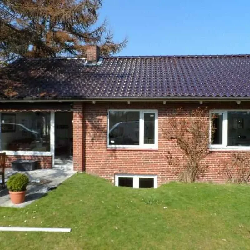 Gartenansicht eines Backsteinhauses mit neuen Fenstern von NORTA. Hochwertige Fenster für optimalen Lichteinfall und Isolierung.