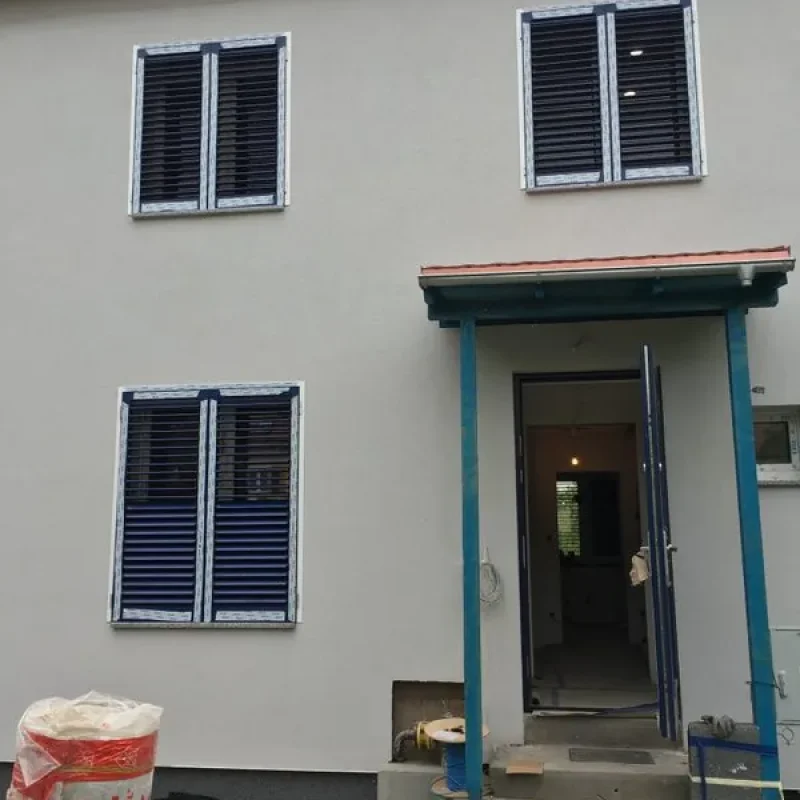 Modernes Haus mit blauen Aluminium-Raffstoren an Fenstern. Stilvoller Sonnenschutz und Privatsphäre von NORTA.