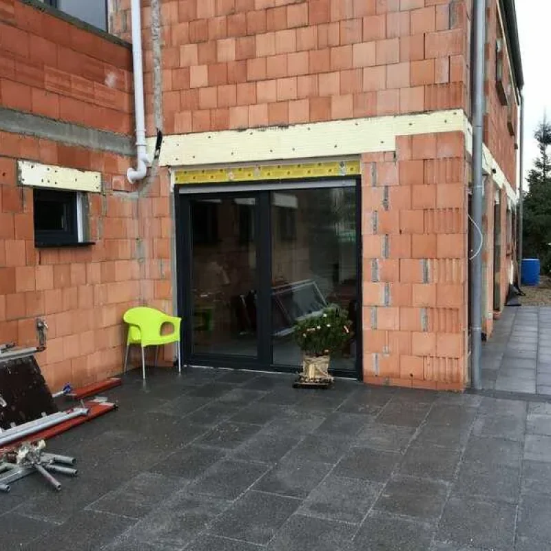 Modernes Fenster in Grau von NORTA, eingebaut in unverputzter Wand. Hochwertige Lösung für optimale Dämmung und Lichtdurchlass.