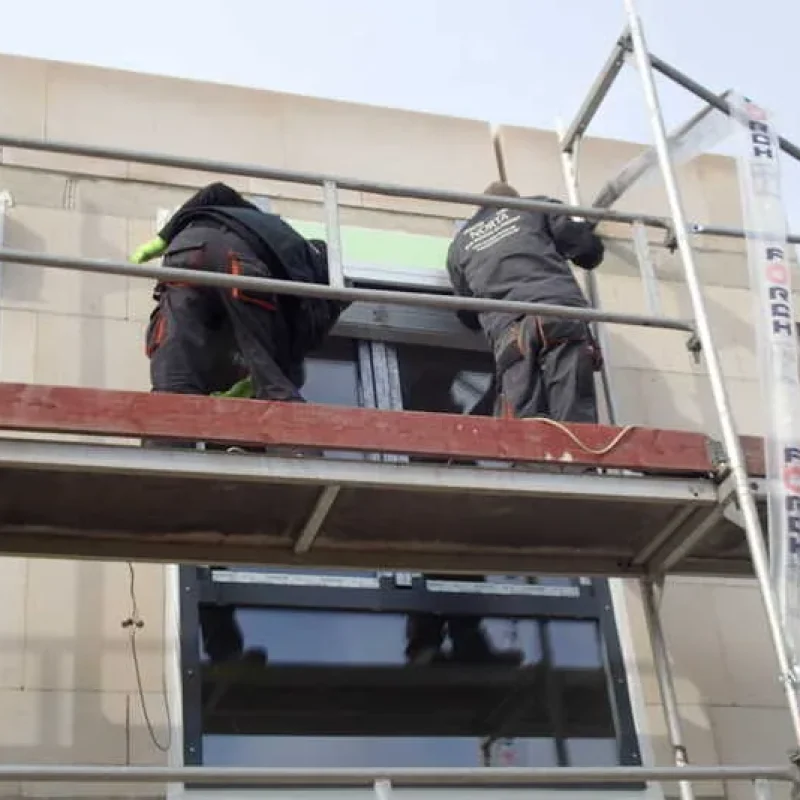 Fenstermontage mit Schüco Fenstern an einem Einfamilienhaus von NORTA. Arbeiter auf Gerüst sichern energieeffiziente Fenster.