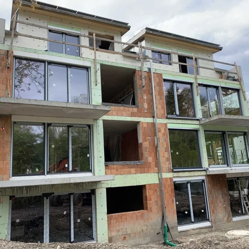 Große Fensterfronten in einem Neubau in München von NORTA. Moderne, lichtdurchflutete Architektur für nachhaltiges Wohnen.