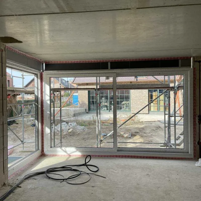 Große Fensterfront mit modernem Rahmen von NORTA. Lichtdurchfluteter Wohnraum mit Blick auf Baustelle.