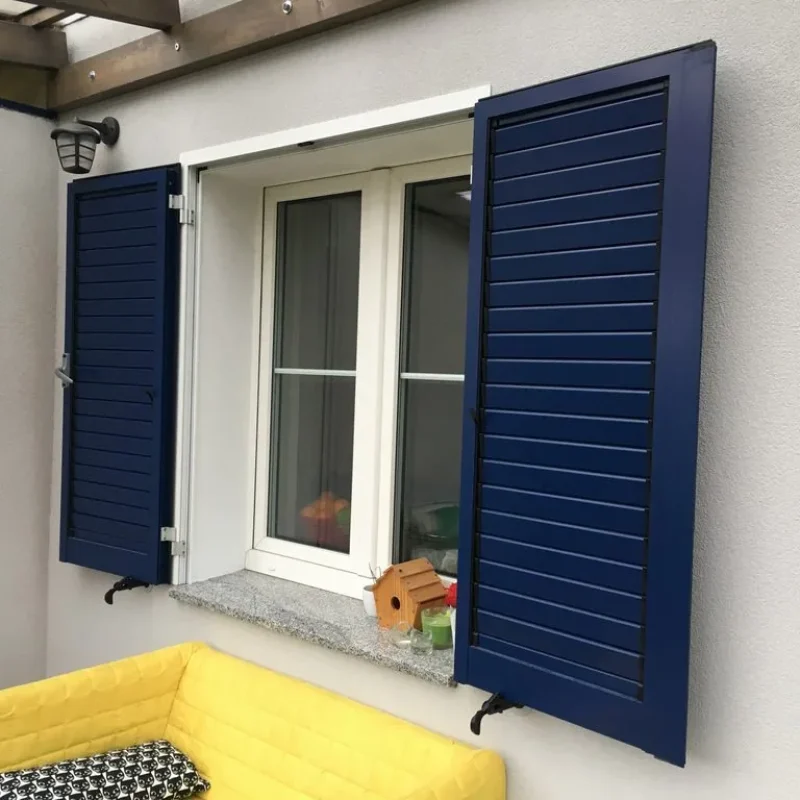 Blauer Aluminium-Fensterladen von NORTA. Stilvolle Lösung für Witterungsschutz und Privatsphäre bei Fenstern.