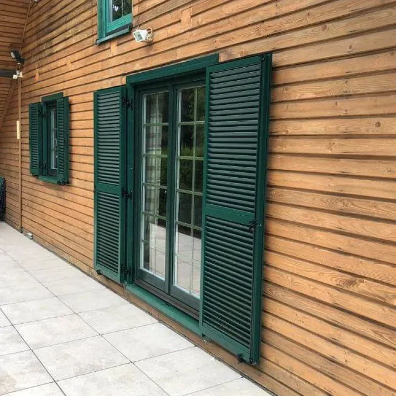 Grüne Fensterläden aus Aluminiumprofilen von NORTA. Langlebig und stilvoll für optimalen Sichtschutz bei Fenstern.
