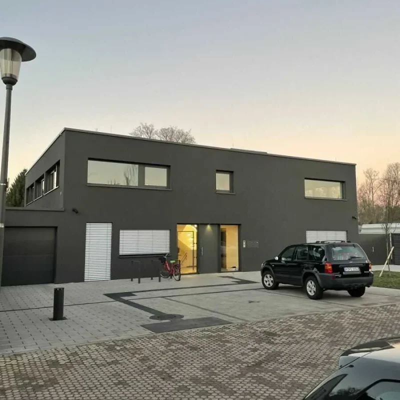 Modernes Gebäude mit dunkler Fassade, Fenstern und Tür im Vordergrund. Hochwertige Architektur von NORTA.