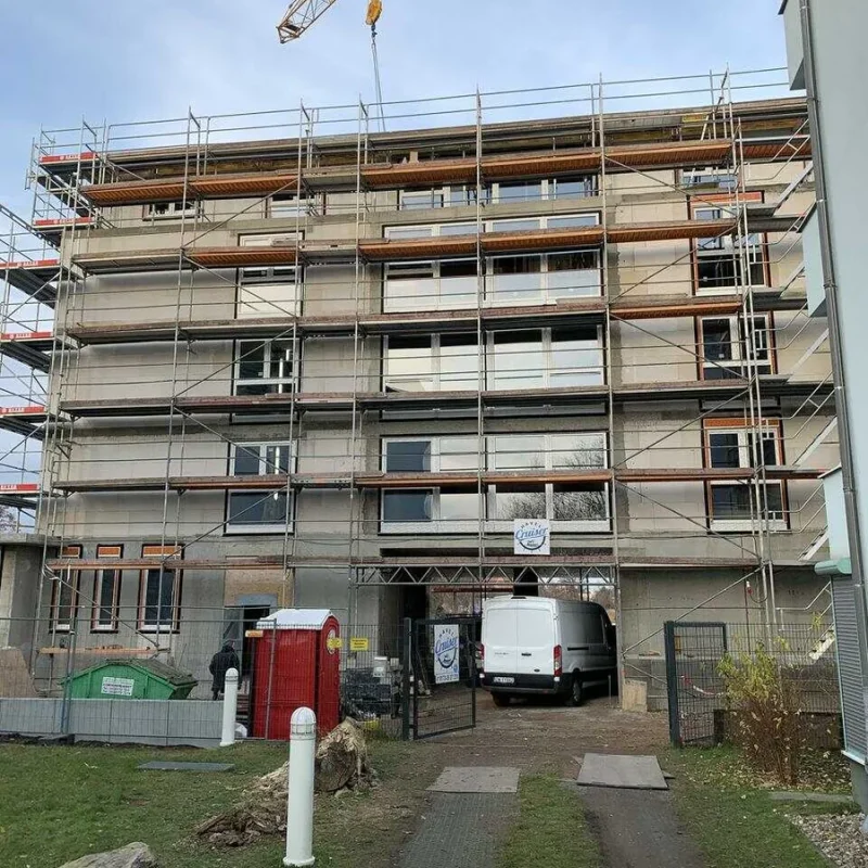 Mehrfamilienhaus im Bau mit Gerüst und Kran. Moderne Fensterlösungen von NORTA für energieeffiziente Neubauten.