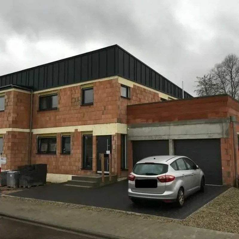 Modernes Wohnhaus im Rohbau mit Backstein und dunklem Flachdach von NORTA. Energieeffizientes Design und zukunftssicheres Wohnen.