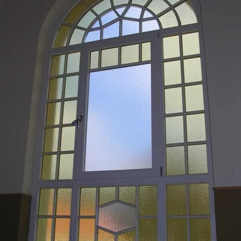 Historisches Rundbogenfenster mit weißem Rahmen und Ornamentglas von NORTA, ideal für klassische Architektur und hochwertigen Lichtschutz.