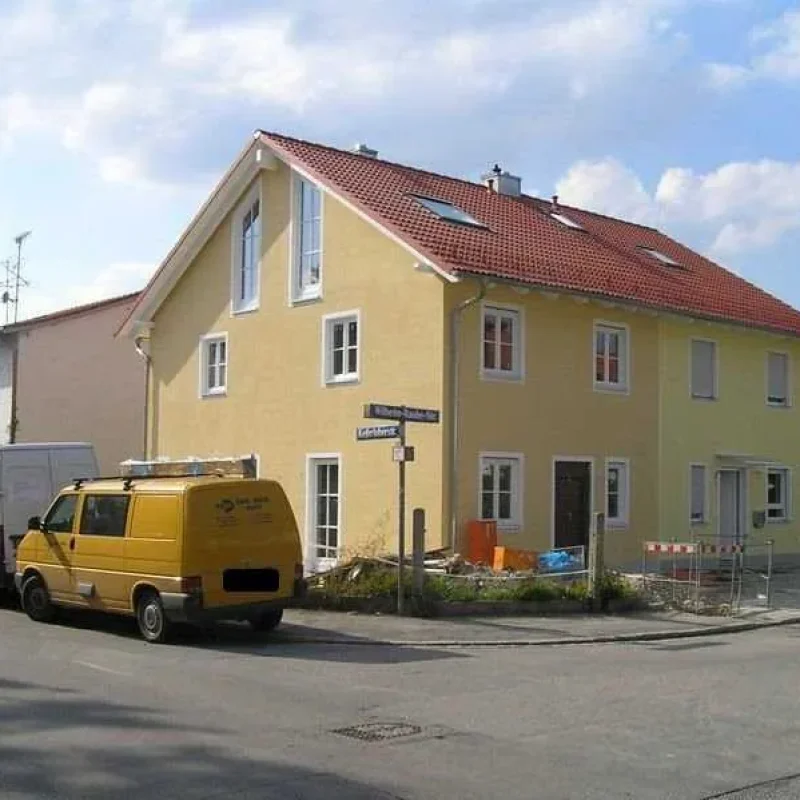 Haus mit Holzfenstern in München von NORTA. Hochwertige Lösung mit dreifacher Verglasung und gelber Fassade für Energieeffizienz.