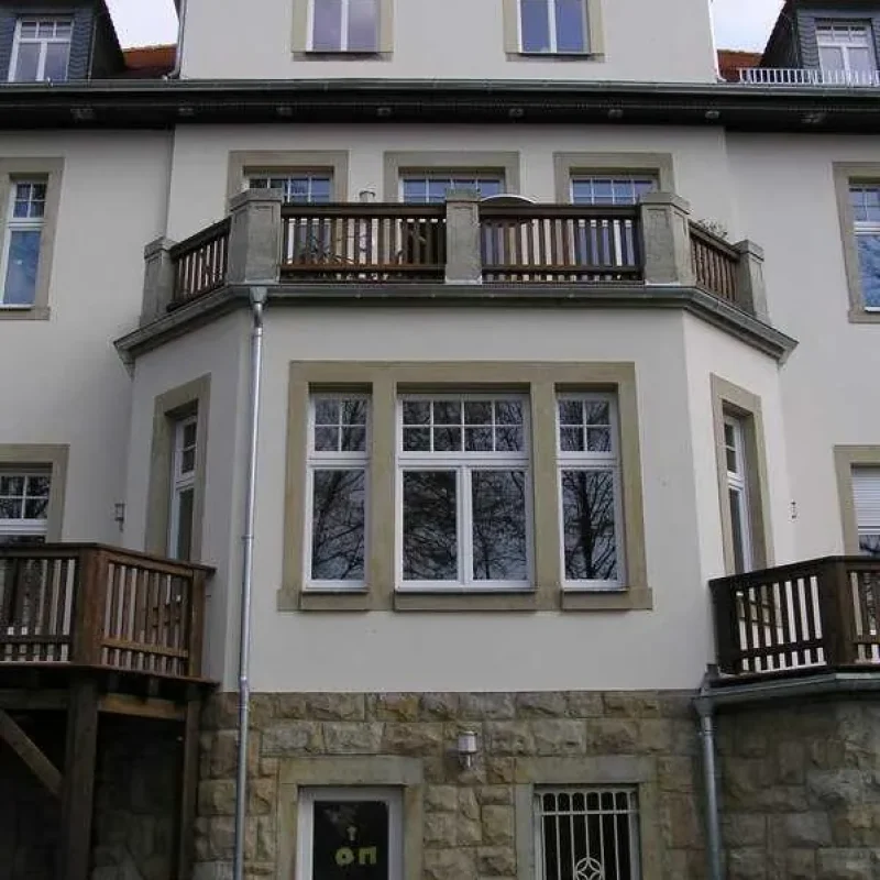 Renoviertes Mehrfamilienhaus mit neuen Fenstern und Balkon aus Stein und Holz von NORTA. Elegante Wohnlösung.
