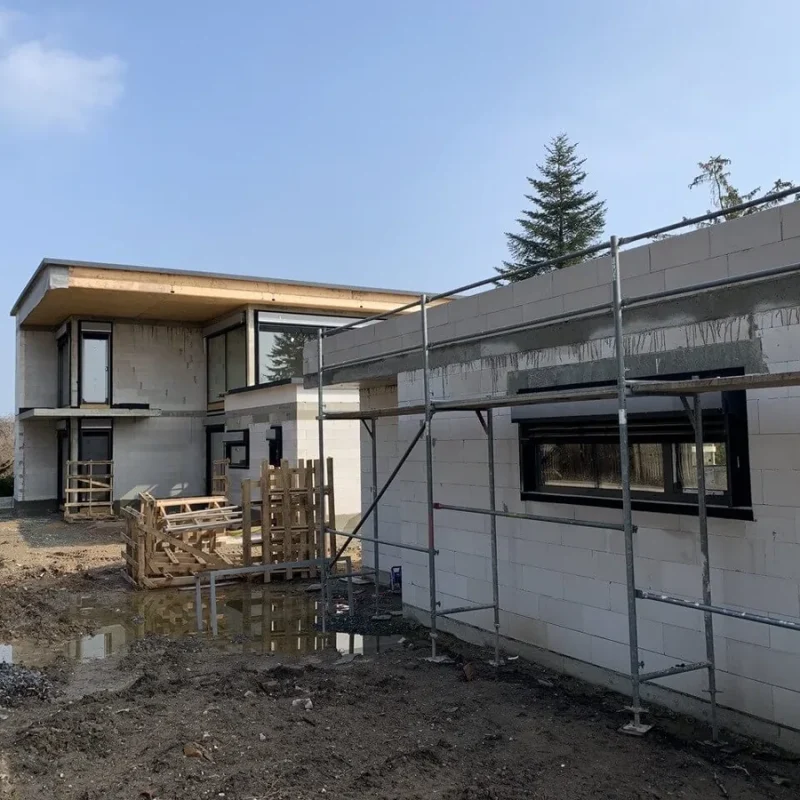 Modernes Einfamilienhaus im Bau mit großen Fenstern von NORTA, eingebettet in eine ländliche Umgebung.