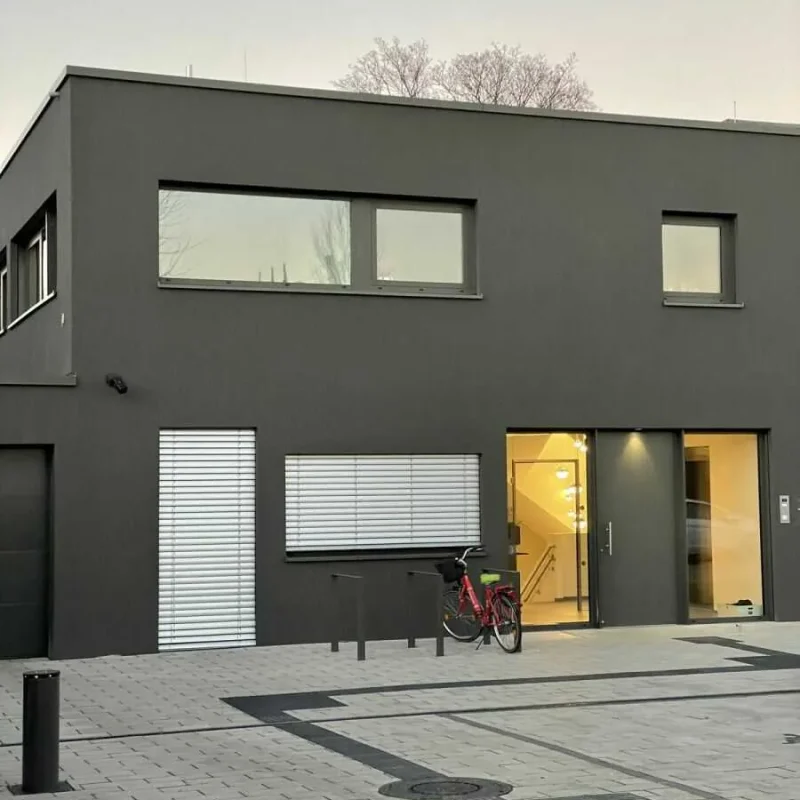 Modernes Gebäude in Köln mit großen Fenstern und dunkelgrauer Fassade von NORTA. Hochwertige Architektur für urbane Umgebungen.