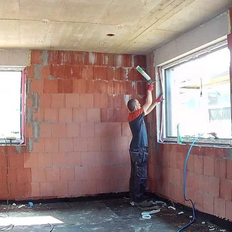 Arbeiter bei der Fensterinstallation in einem Rohbau. Robuste Fensterlösungen von NORTA für optimale Dämmung und Lichteinfall.