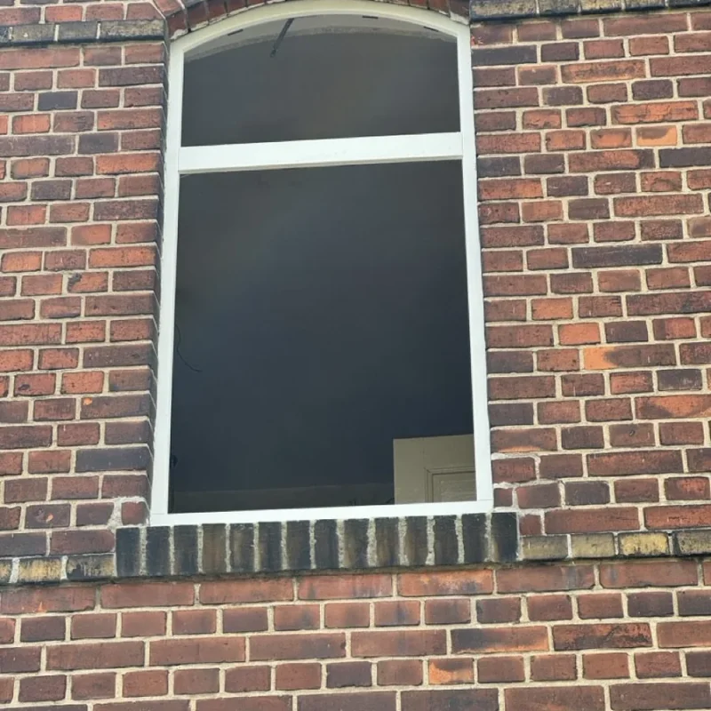 Montage eines Holzfensters in eine Backsteinfassade. NORTA gewährleistet hochwertige Installation und optimale Isolierung.