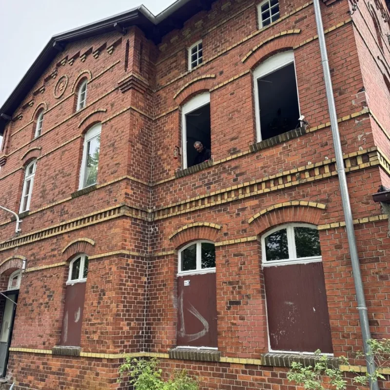 Backsteingebäude mit Fenstern während der Montage von Holzfenstern. NORTA sorgt für hochwertigen Einbau.