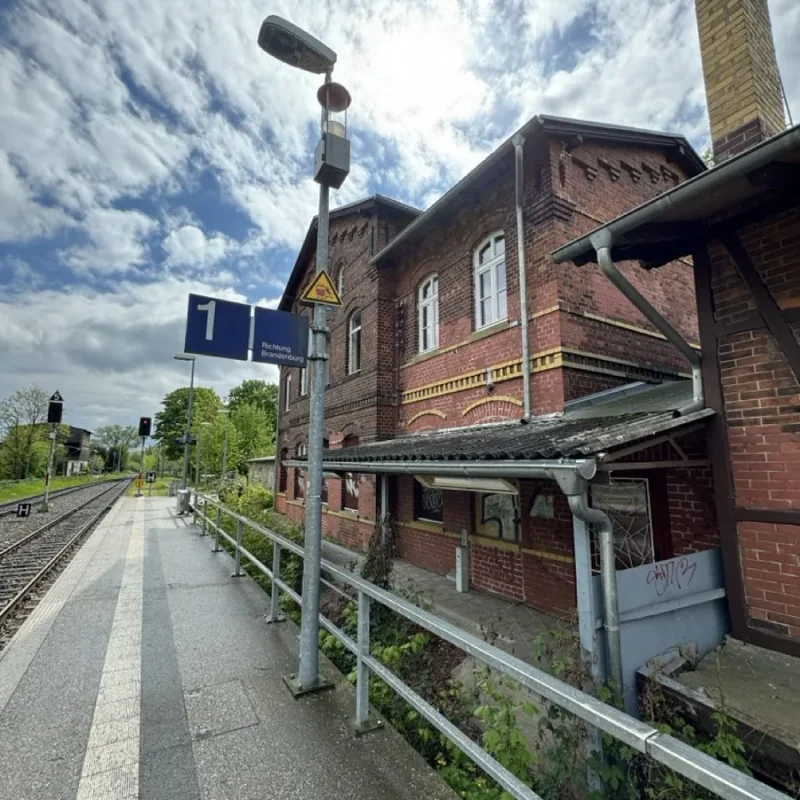 Alter Bahnhof in Havelsee mit markantem Backsteingebäude unter bewölktem Himmel, an einem Bahngleis gelegen.