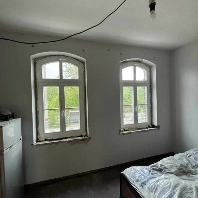 Innenansicht eines Raumes mit neuer Holzfenster-Montage von NORTA. Perfekter Sitz und bessere Energieeffizienz.
