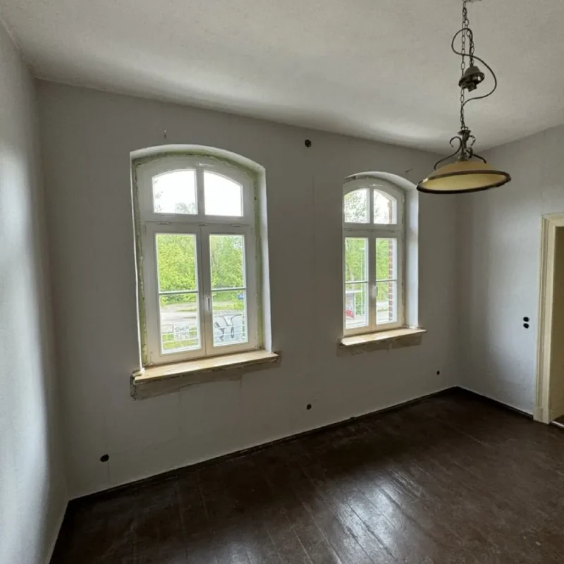 Elegante Holzfenster mit klassischem Bogen im Raum von NORTA. Erhellen das Zimmer natürlich und bieten zeitlose Ästhetik.