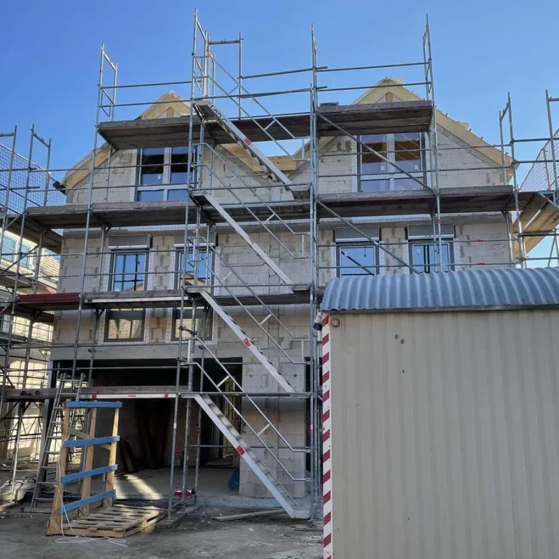 Neubau eines Doppelhauses in Köln mit Gerüst. Energieeffiziente Bauweise mit Einsatz moderner Fensterlösungen von NORTA.
