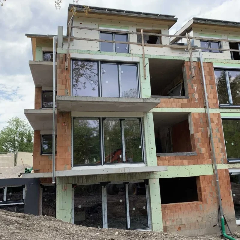 Moderne Fensterfront eines Neubaus von NORTA. Große Glasflächen für viel Tageslicht und energieeffiziente Wohnräume.