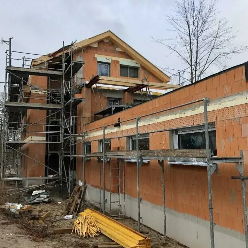 Rohbau eines Hauses mit Fenstermontage von NORTA. Hochwertige Installationen für effiziente Energieeinsparung.