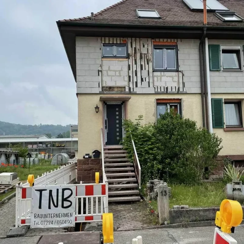 Fassade eines Hauses in Gernsbach während Sanierungsarbeiten. Baustelle mit Absperrung von TNB Bauunternehmen. Hochwertige Sanierungslösung.